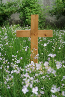 Kreuz aus Holz in einer Wiese