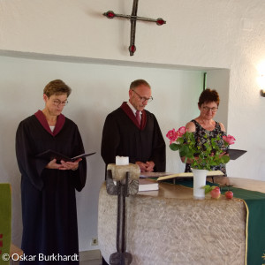 das Vorbereitungsteam (Prädikantin Gertraud Burkhardt, Lektor Werner Schlöger und Heidi Raab sprechen hinter dem Altar stehend ein Gebet